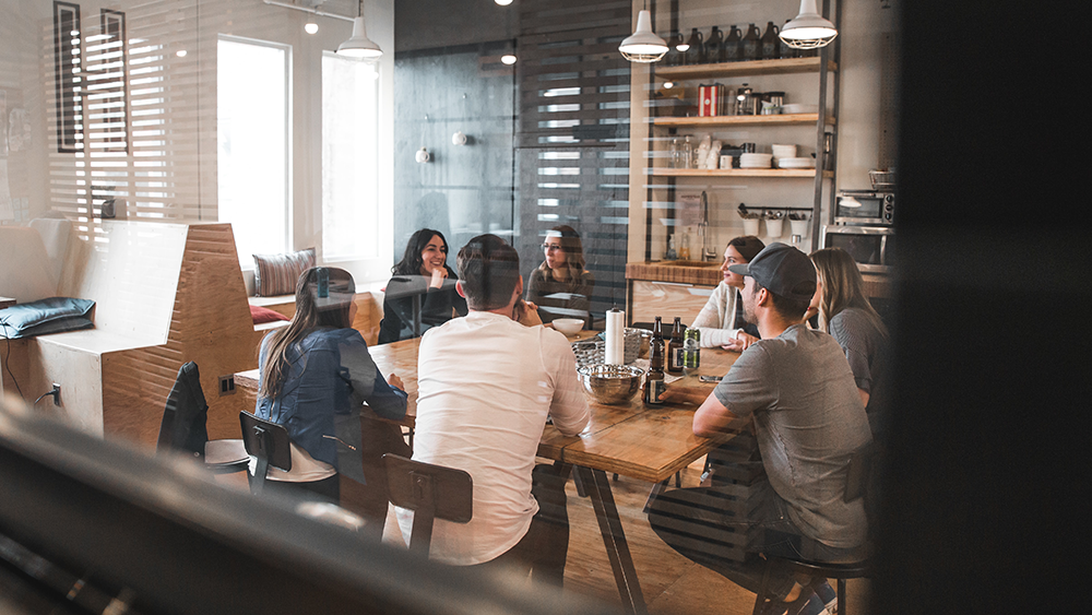 A group of people sit around a table in a meeting room. 